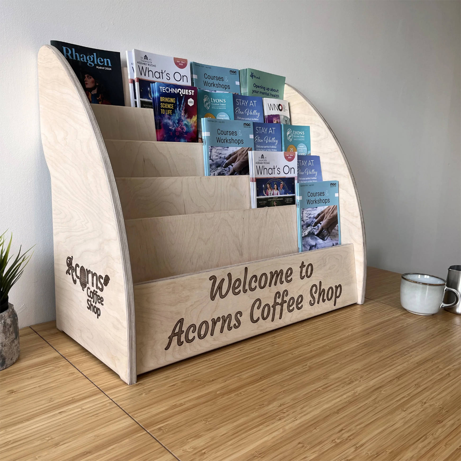 Wooden leaflet holder shown in coffee shop setting with custom engraving example.