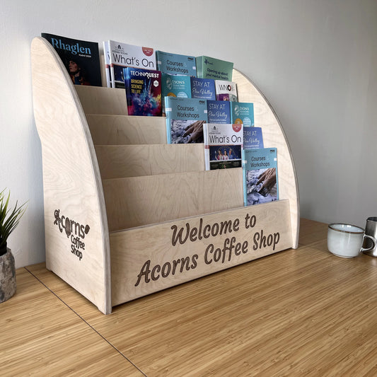 Wooden leaflet holder shown in coffee shop setting with custom engraving example.